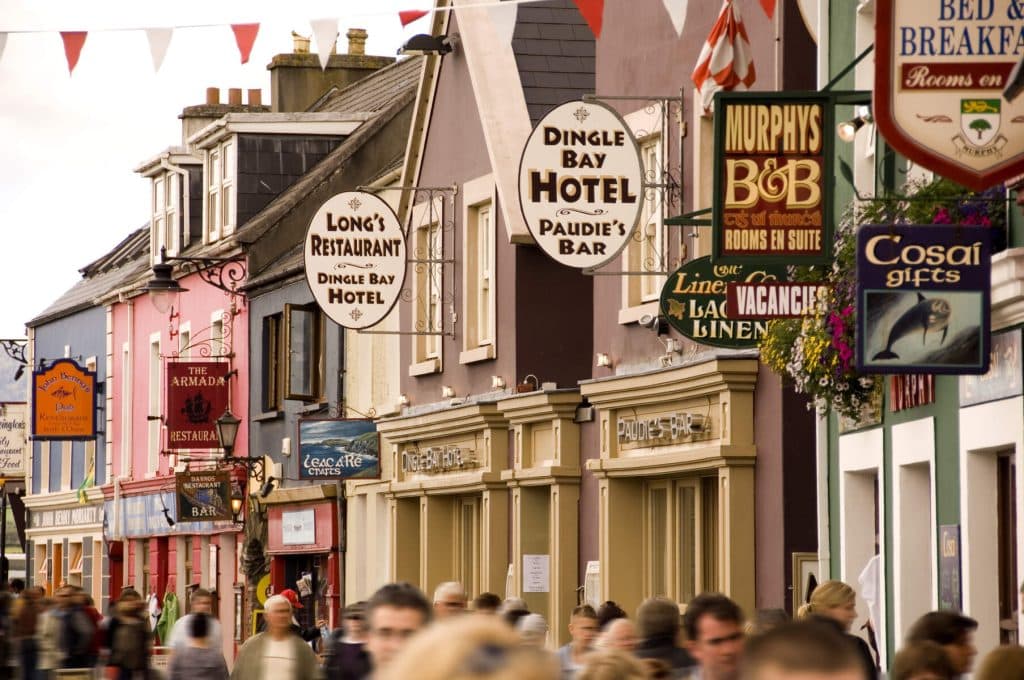 Shop fronts and hanging signs along a street in Dingle. Dingle is one of the best towns in Ireland for a break.
