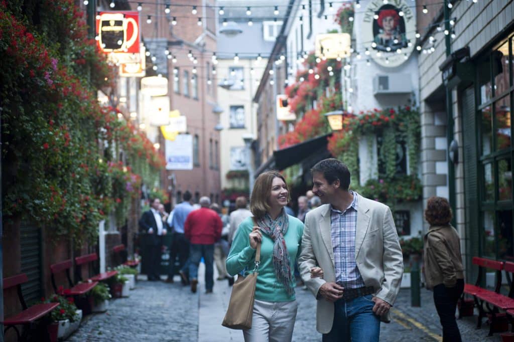 A couple strolling arm-in-arm through Belfast's Commercial Court.