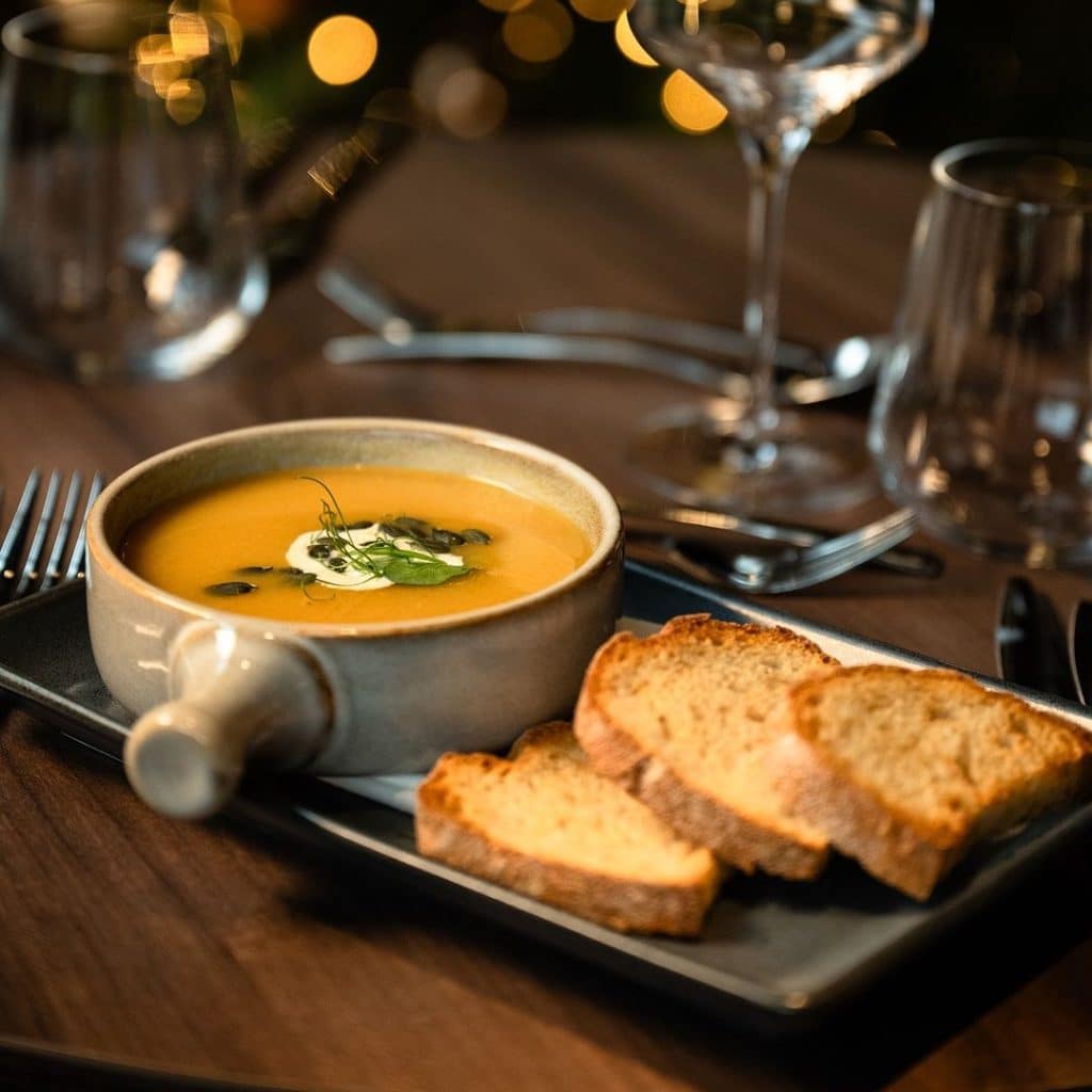 A comforting bowl of butternut squash soup served alongside slices of crusty bread.