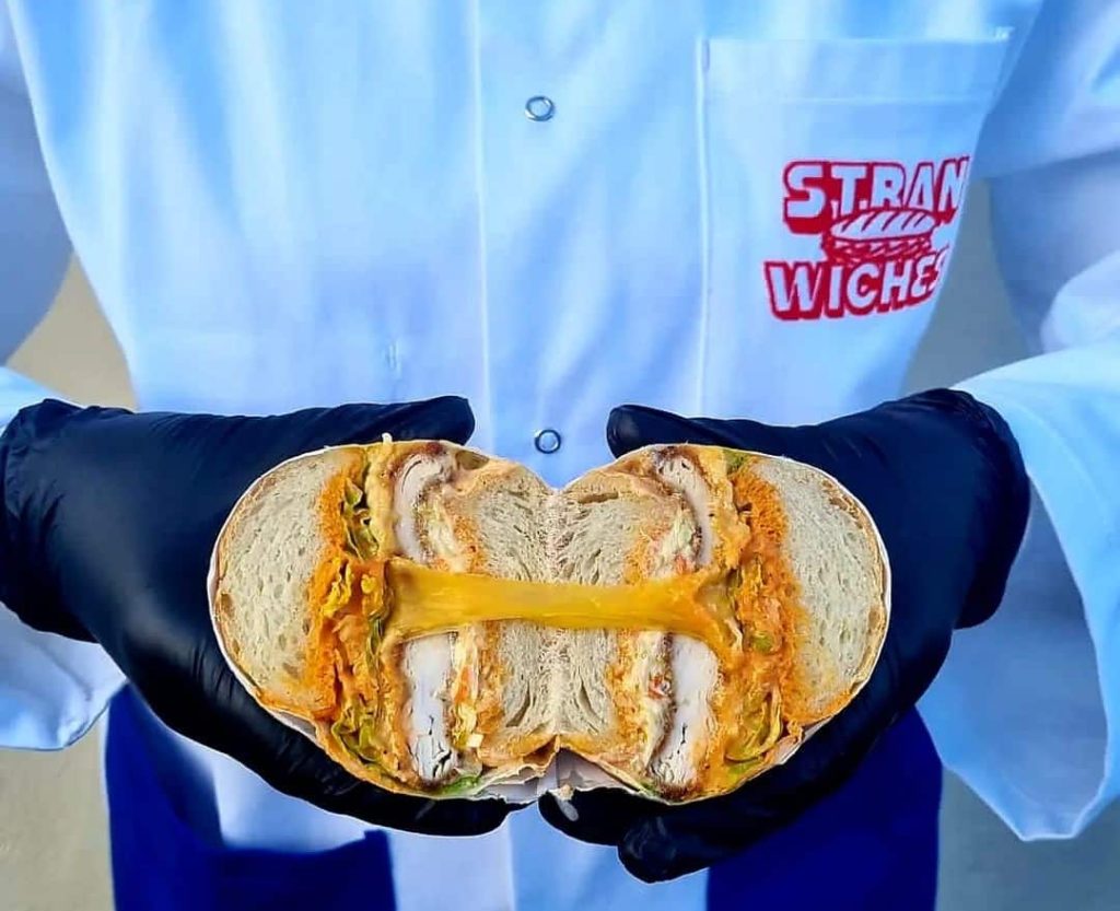 A close-up photo of a delicious sliced sandwich from Stranwiches restaurant, showcasing layers of fresh ingredients between slices of bread, enticingly presented with vibrant colors and textures.