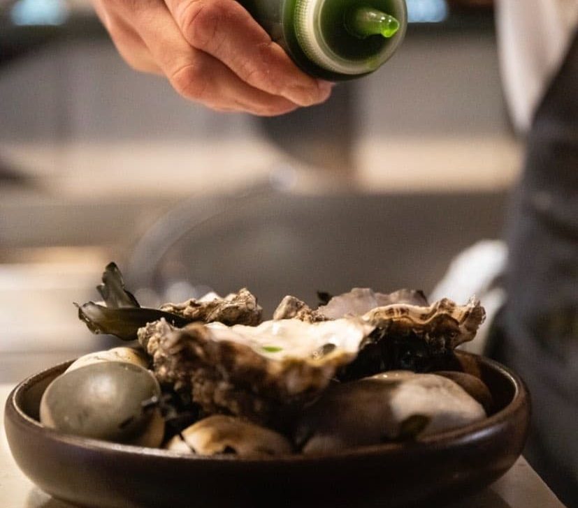 A chef delicately garnishes an oyster dish.