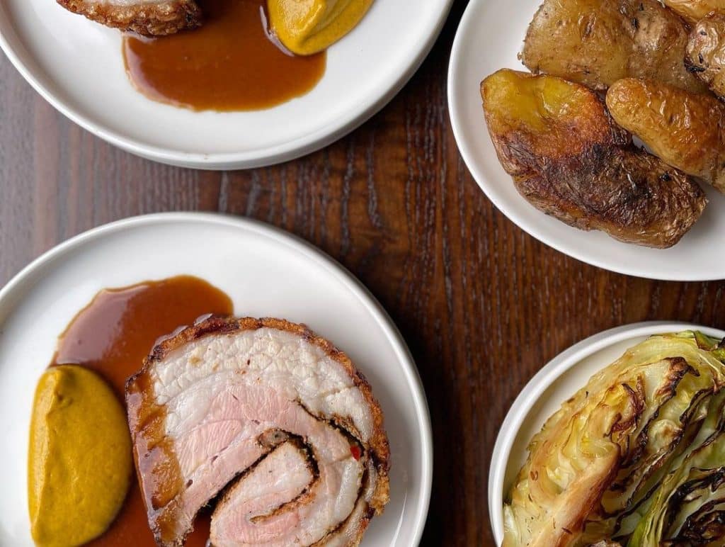 A succulent and aromatic porchetta, a traditional Italian roasted pork dish, is expertly prepared with crispy skin and juicy, flavorful meat, ready to be served and enjoyed.