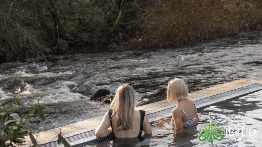 Two women in an outdoor pool looking out at a river.