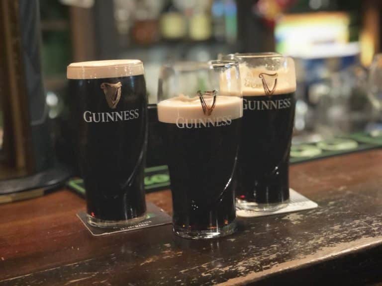 Pints of Guinness sitting on a bar.