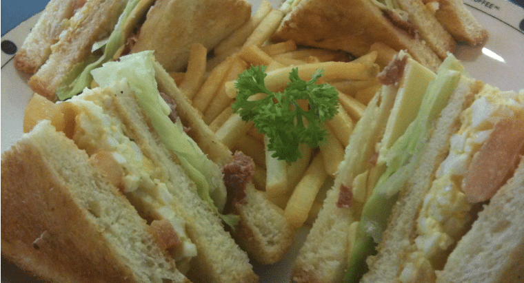 A close-up shot of several triangular sandwiches representing the traditional "funeral sandwich" served during Irish wakes.