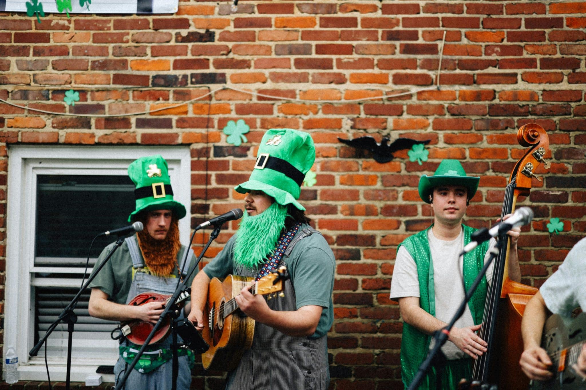 A photo of a band playing in the street, dressed in leprechaun costumes.