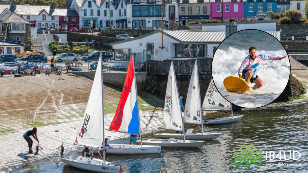 A bustling harbor boat slip filled with small sailboats, overlaid with a circular graphic of a man surfing and the Ireland Before You Die logo.