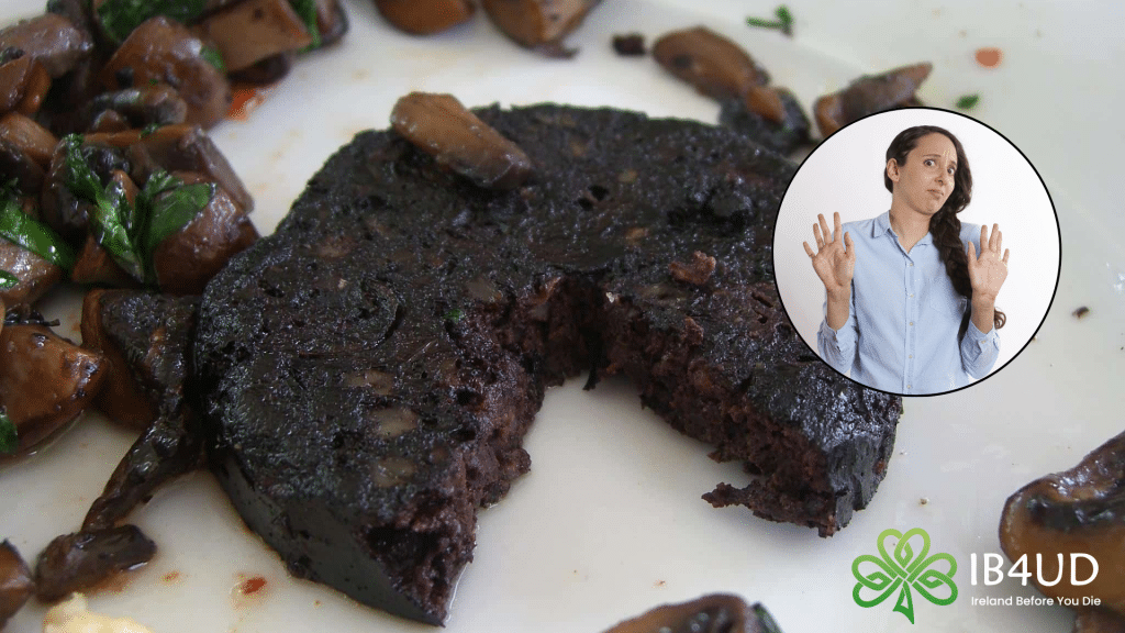 A close-up of a thick, fried slice of Irish black pudding on a plate with sautéed mushrooms, featuring a circular graphic of a woman making a hesitant, refusing gesture.