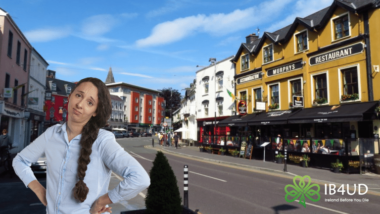 A woman with a skeptical expression and hands on her hips is superimposed over a sunny street scene in Killarney town centre.