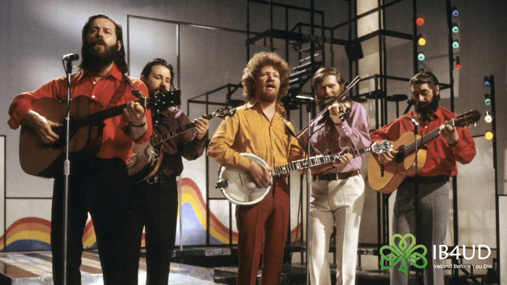The Irish folk band The Dubliners performing on a stage set playing guitars, banjos, and a fiddle.